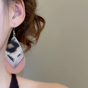 Macro shot of three-layer teardrop earrings with leopard print and silver texture on a model