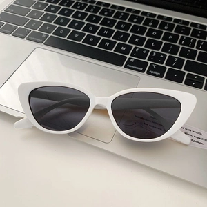 Close-up of white cat-eye sunglasses with dark lenses on a laptop keyboard