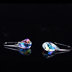Detailed macro of iridescent teardrop crystal earrings with silver hooks and fire reflection