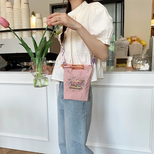 Detailed embroidery of a colorful carousel on a pink oxford cloth mini crossbody bag