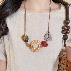 Detail of bohemian necklace with woven rattan ring and amber resin marble beads