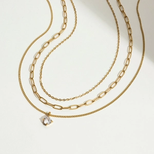 Détail d'un collier triple rang en or avec chaîne trombone et pendentif zircon rond