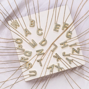 Gold plated initial letter necklace with cubic zirconia pendants on light background