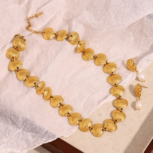Détail d'un ensemble de bijoux avec collier coquillage doré 18K et boucles d'oreilles perles