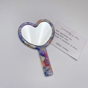 Macro detail of heart-shaped acetate mirror with colorful marble texture on white background