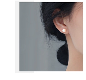 Close-up of elegant round pearl stud earring worn by model with minimalist aesthetic