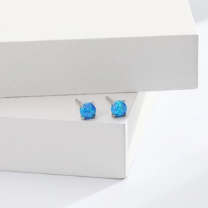 Detail view of round blue opal stud earrings with classic four-prong silver setting