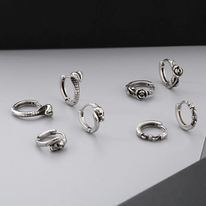 Detailed macro view of vintage silver punk hoop earrings with snake and rose motifs