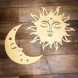 Detailed view of sun and moon wooden wall art with carved faces on dark wood background