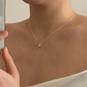 Detail of 925 sterling silver chain necklace with a round zircon pendant on a person