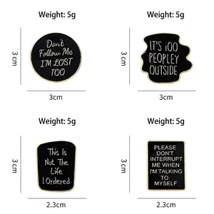 Set of four black enamel badges with white quotes and golden alloy frames in a grid layout