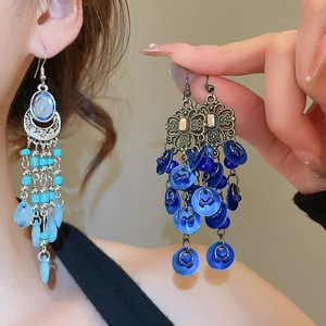 Detailed macro view of bohemian shell earrings with blue beads and long fringe tassels
