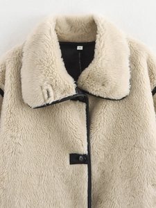 Detail of cream plush jacket featuring black leather trim and soft lamb-like texture