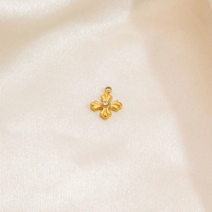 Detailed close-up of a gold cross pendant with a white zircon on champagne silk fabric