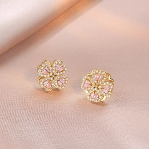 Close-up of gold flower earrings with pink pear-cut stones and white zircon pavé setting