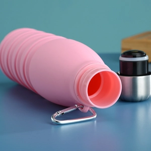 Close-up of pink collapsible silicone water bottle with wave design and metal carabiner