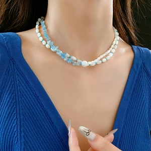 Detail of double-layer necklace featuring white shell beads and blue aquamarine stones