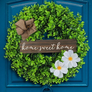 Artificial boxwood wreath with home sweet home sign and bow on blue door