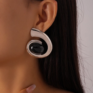 Détail d'une boucle d'oreille spirale argentée avec pierre onyx noire sur un mannequin
