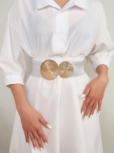 Close-up of elastic silver belt with dual gold textured round buckles on white dress