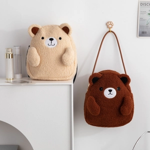 Close-up of plush teddy bear shoulder bags in apricot and brown with soft faux fur texture