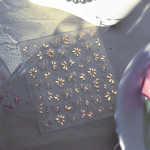 Detail of gold metallic butterfly and floral nail art stickers with glossy texture