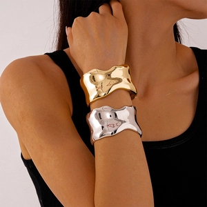 Minimalist wide wavy gold and silver metal bangles with a polished mirror finish on model