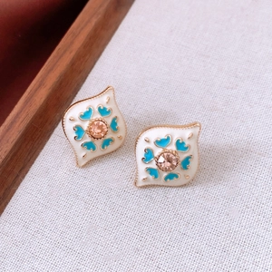 Detail of vintage gold earrings with white enamel blue hearts and pink center gems