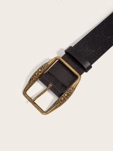 Close-up of black embossed leather belt with a vintage bronze engraved metal buckle
