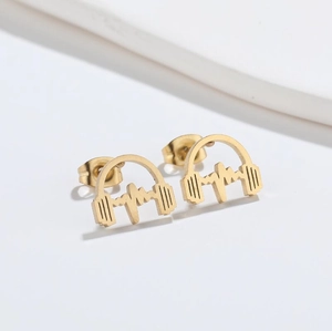 Macro shot of gold headphone and heartbeat stud earrings in minimalist style