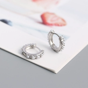 Macro shot of silver S925 sterling silver hoop earrings with delicate inlaid pearls