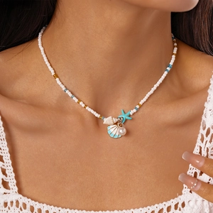 Close-up of beaded beach necklace with shell, starfish, and pearl charms on model