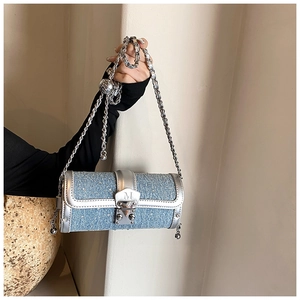 Detail of blue denim cylinder bag featuring sparkling sequins and silver leather trim