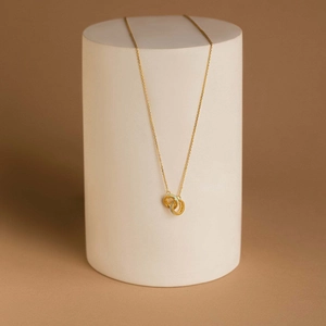 Detail of interlocking gold rings on a delicate chain pendant with soft studio lighting