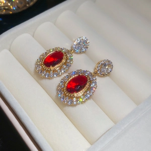 Close-up of vintage gold earrings with oval red gemstone and pavé zircon detailing