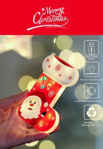 Detail of red Christmas stocking LED light with Santa and snowflake motifs in warm bokeh background