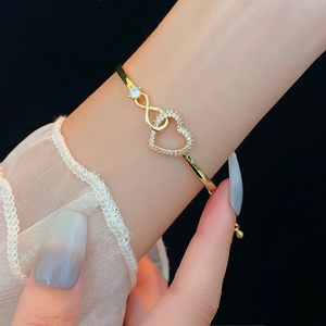 Detail of gold bracelet with zircon-studded heart and infinity symbols on wrist