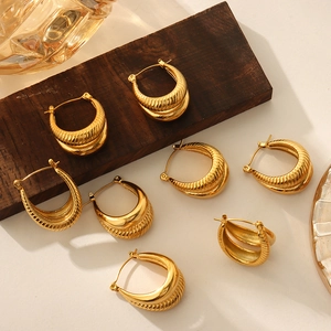 U-shaped gold plated titanium steel hoop earrings with textured twill design on wood base