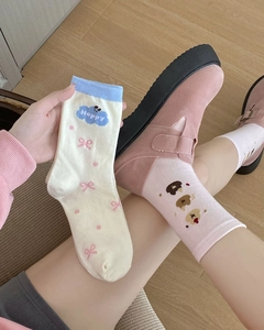 Detail of mid-calf socks with cute dog and bow patterns on model feet and hands