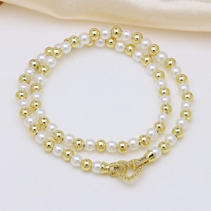 Macro detail of natural pearl necklace with golden beads and a rhinestone heart clasp