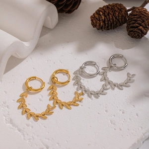 Elegant gold and silver leaf tassel earrings displayed on a white textured stone surface