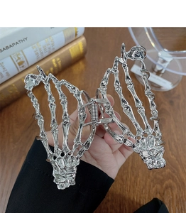 Detailed close-up of a silver gothic skeleton hand metal hair claw clip with a chrome finish
