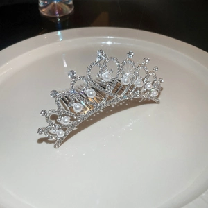 Détail d'une couronne de mariée argentée avec strass et perles sur plateau céramique