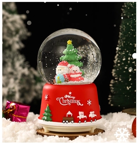 Detail of a Christmas snow globe featuring Santa Claus and tree on a red Merry Christmas base