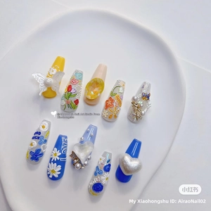 Detail of 3D embossed floral nail art charms with heart and butterfly on a white tray