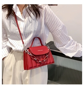 Detailed view of red quilted leather crossbody bag with chain and brand logo detail