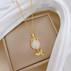 Close-up of golden tulip necklace with white gemstone set on elegant silk fabric