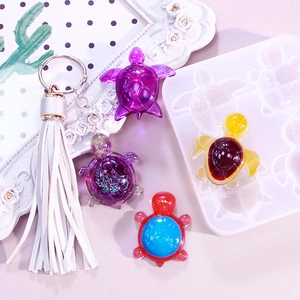 DIY turtle silicone mold and finished resin turtle keychains with tassels on pink background