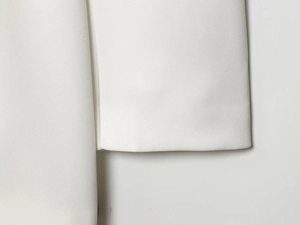 Détail de la robe blanche à double boutonnage montrant la texture du tissu de qualité