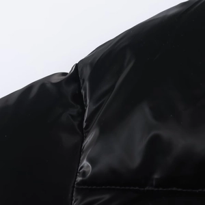 Detailed close-up of glossy waterproof black quilted jacket fabric with premium stitching